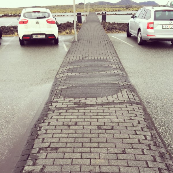 Parking lot with elevated pedestrian pathway that doubles as speed control ramp device.