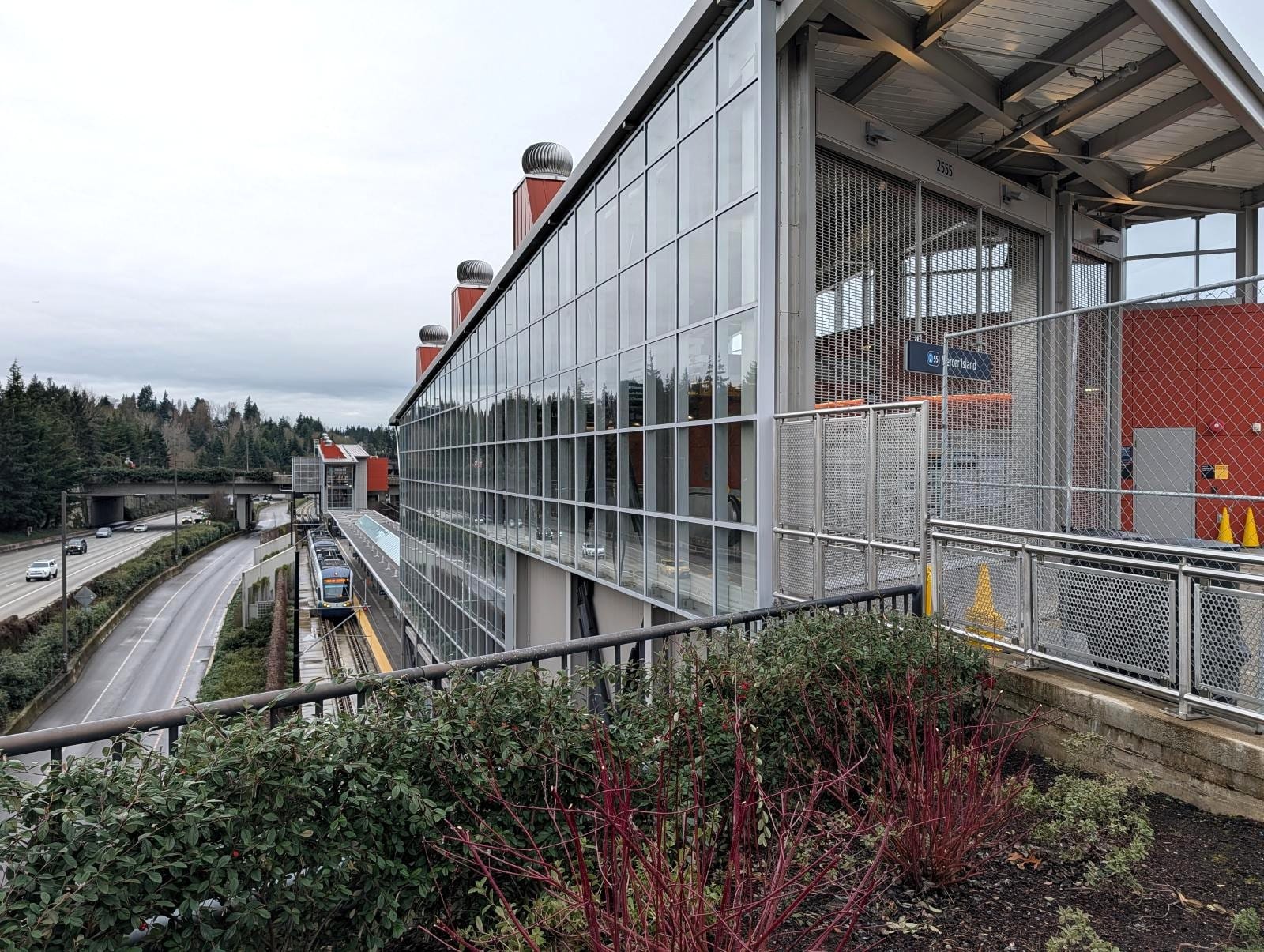 A view from the city street looking down on the light rail station in the median of the freeway.