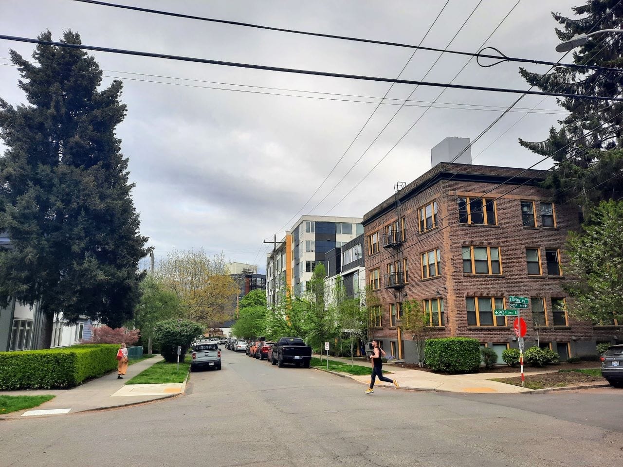 A jogger cross a quiet street in a neighborhood of four- and five-story apartment buildings.