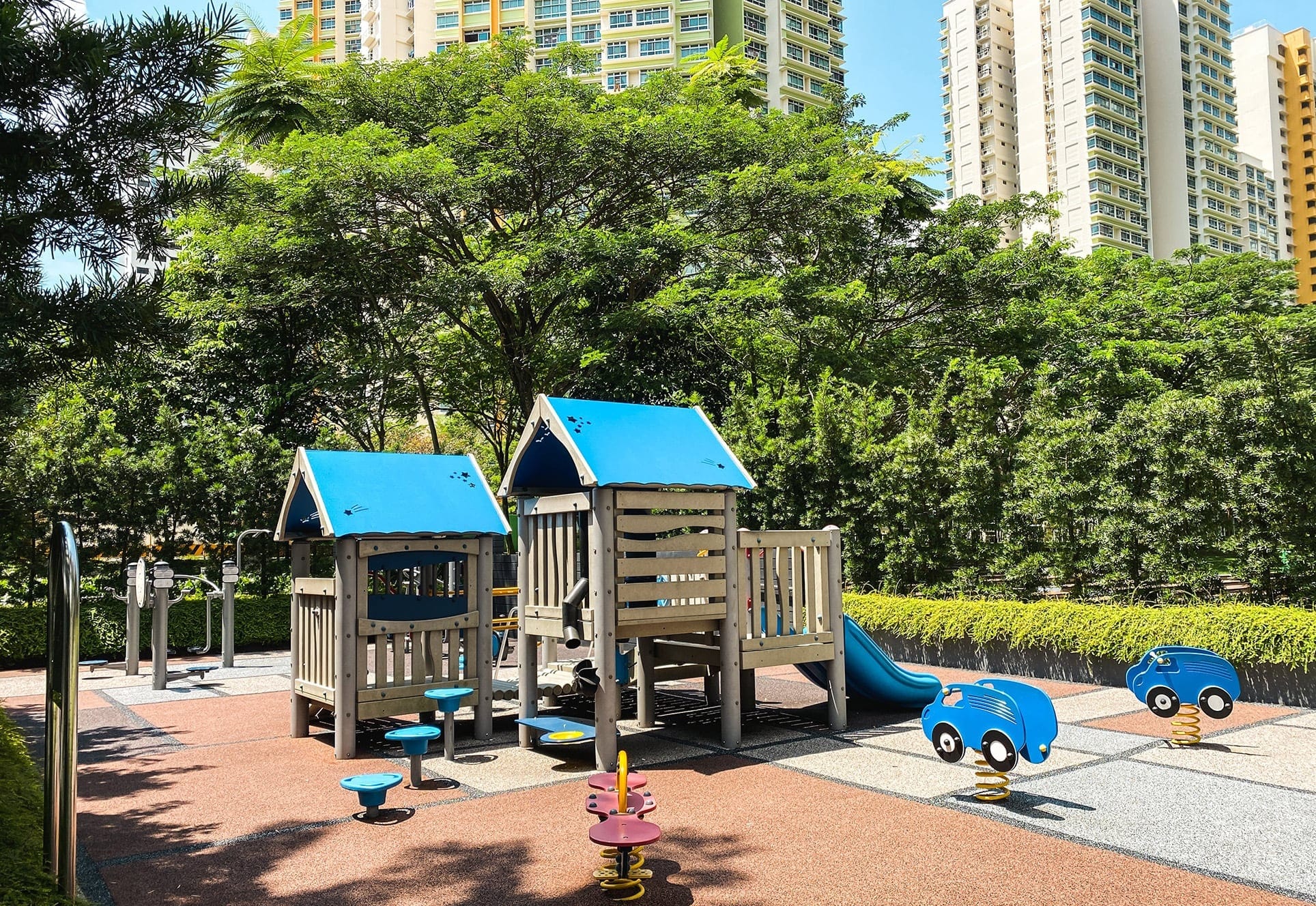 
                     A playground with trees and public housing towers in the background
                     