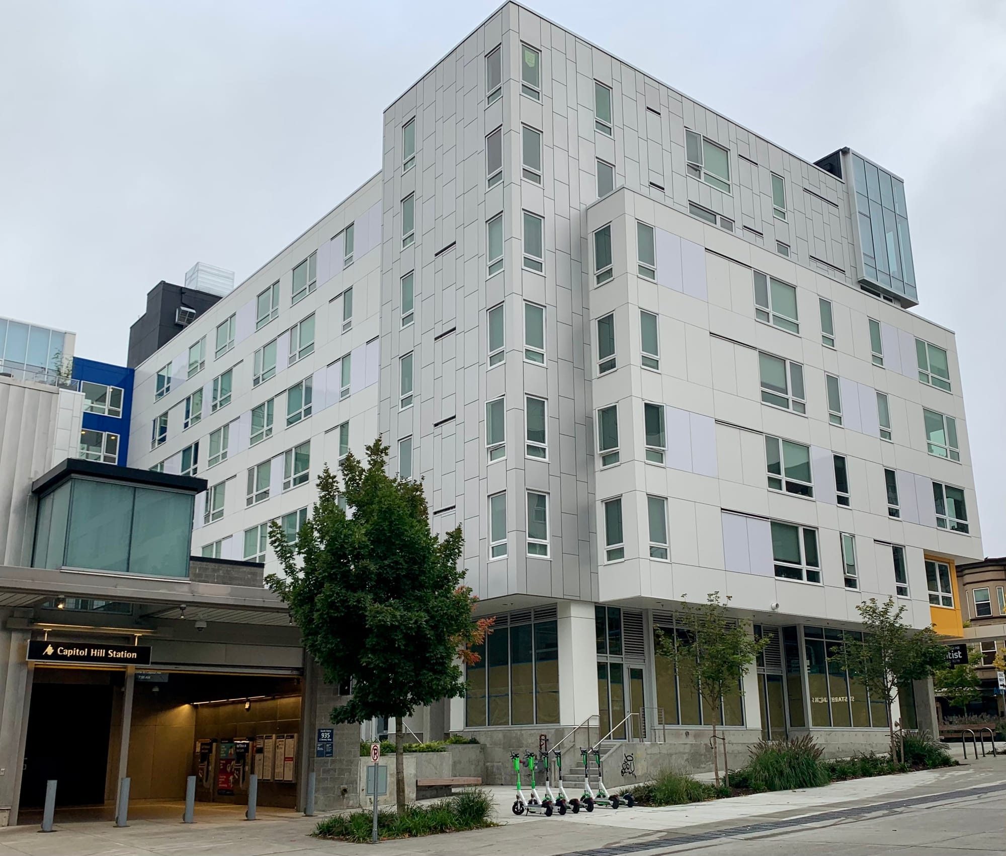 a photo of a six story apartment building constructed next to a light rail station in Capitol Hill