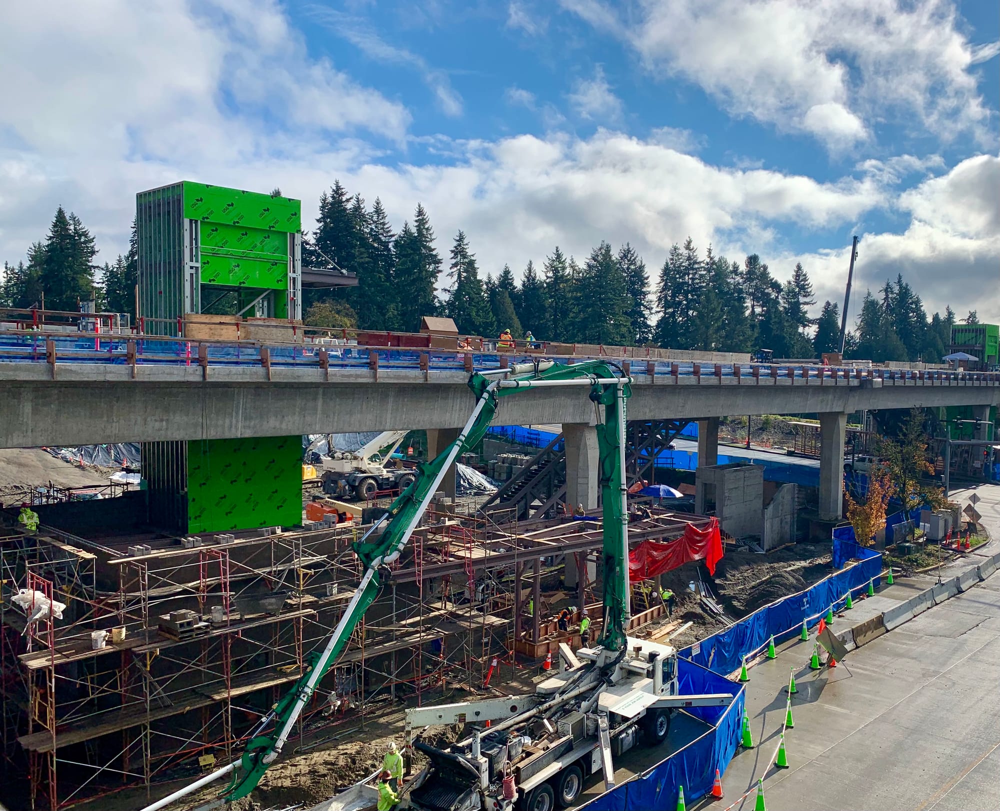 A photo of light rail tracks and a station with elevator in construction. 