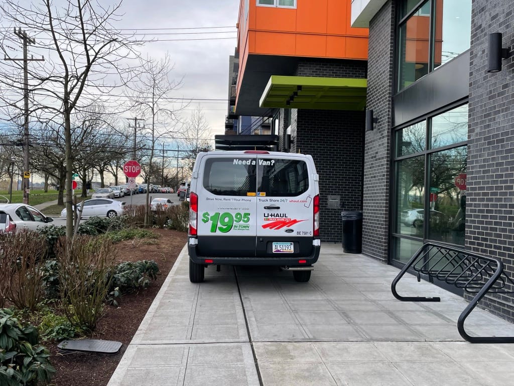 A moving van blocking the sidewalk one block from the Othello Link Station.
