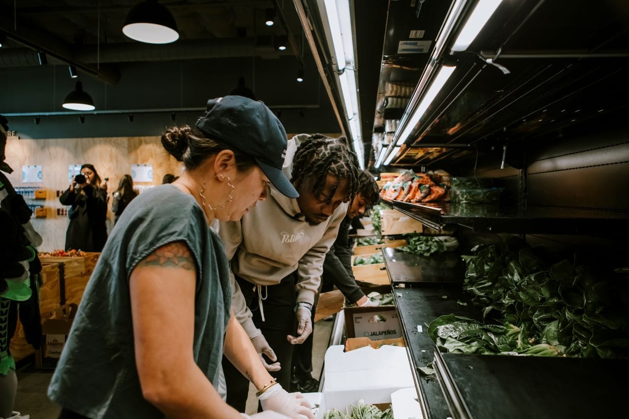 Chunn and another workers sort vegetables out of a row of bins.
