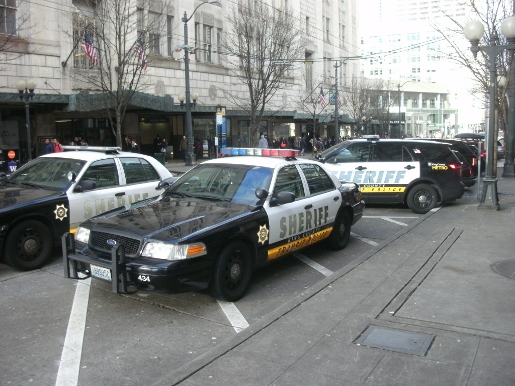 Several sheriff vehicles park on Pine Street in Downtown Seattle next to the light rail station.