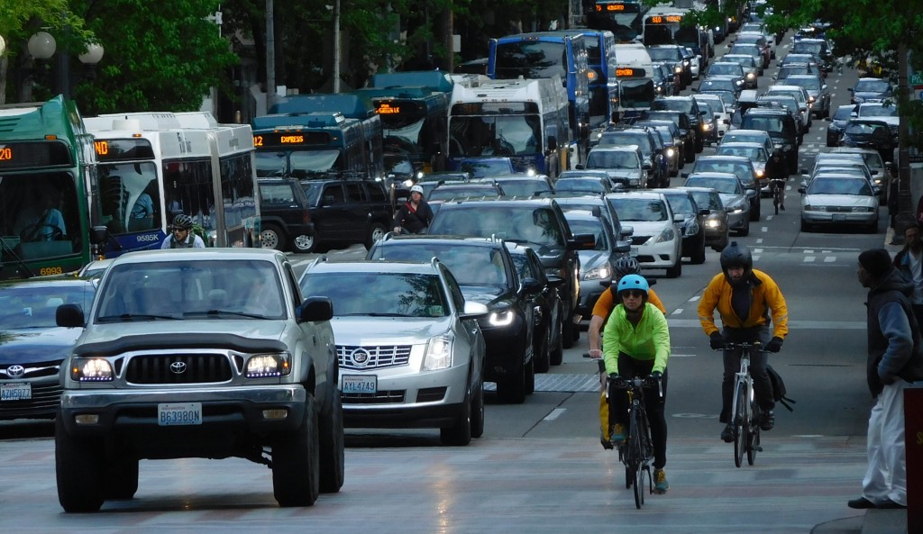 A snarl of car traffic on 4th Avenue with transit and people biking on the margins. (Photo by Scott Bonjukian)