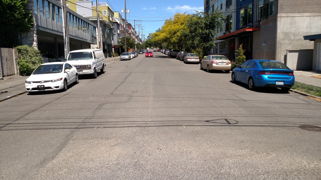 A wide empty street with parking on both sides. 
