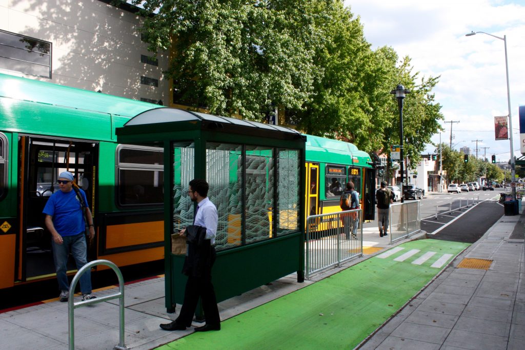 At bus stops, the bike lane wraps behind the shelter, providing a safer alignment.