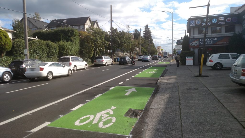 Buffered bike lane near driveways with green paint at curb cuts. 