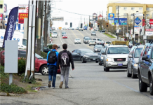 Aurora Avenue: Can a Lost Opportunity Be Regained? Two teens walk along the edge of Aurora with no sidewalk and streams of cars going by.