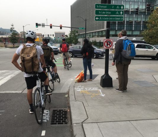 Three Lawmakers Say Their Constituents Should Get a Free Pass on Blocking Seattle Crosswalks and Transit Lanes Three people biking and two pedestrians wait for a long line of cars queuing on Mercer Street in South Lake Union.