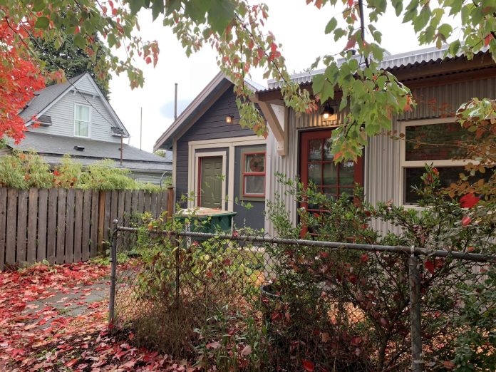 A cottage in a leafy backyard in the fall.