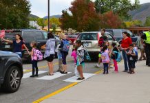 Car-Based School Commutes Hurt Families with Kids A school crosswalk busy with students and parents in a sea of cars.
