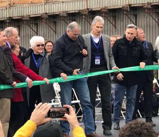 Legislature Must Cut Highway Expansion and Protect Transit, Safety, Maintenance Funds Inslee holds the scissors and other high-level officials look on outside the SR-99 tunnel in February 2019.