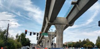 Elevated light rail with pylons next to a street in Northgate.