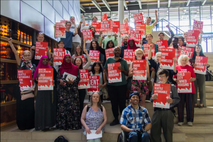 Advocates for rent control Advocates hold red signs backing rent control and housing the homeless.