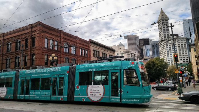 teal streetcar in Pioneer Square with Smith Tower and other buildings
