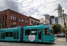Committee Greenlights $9 Million to Continue Center City Streetcar Project teal streetcar in Pioneer Square with Smith Tower and other buildings