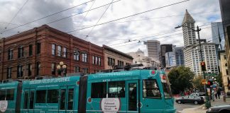 teal streetcar in Pioneer Square with Smith Tower and other buildings