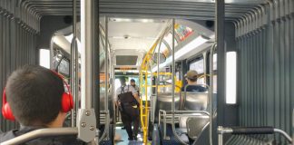 Two fare enforcement officers work their way toward the front of a bus after checking a few riders proof of payment.