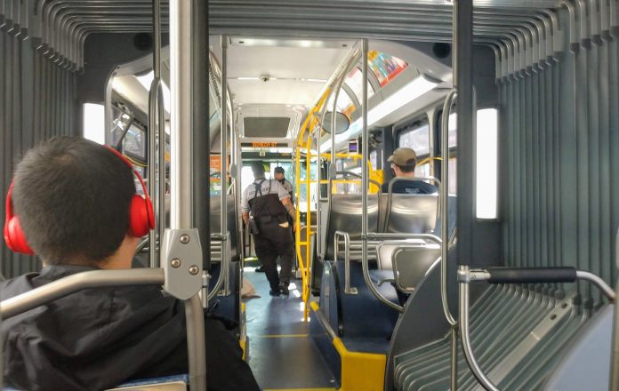 Two fare enforcement officers work their way toward the front of a bus after checking a few riders proof of payment.