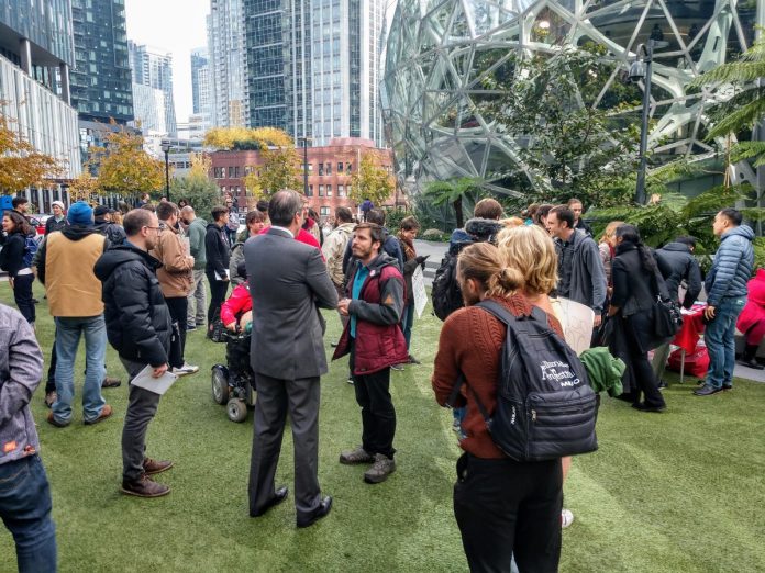 Rally at Amazon Spheres_20191024 An Amazon contract employee who opposed Amazon's copious campaign spending talks to a reporter. before an October 24th rally at the Amazon Spheres. (Photo by author)