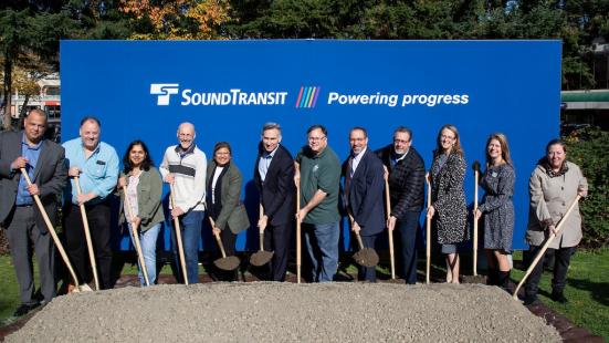 12 officials exercise their shovel arms in this posed photo for the groundbreaking for the Downtown Redmond Link Extension. (Sound Transit)
