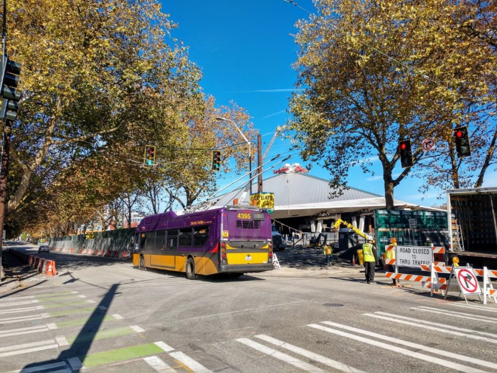 1st Avenue N passes by the busy construction site at Seattle Center Arena. A bus use the right lane, while the protected bike lane is on the left. (Photo by Doug Trumm)