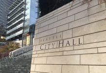 Seattle Needs a 10th Councilmember Downtown Seattle wall with City Hall sign on it and buildings in the background.