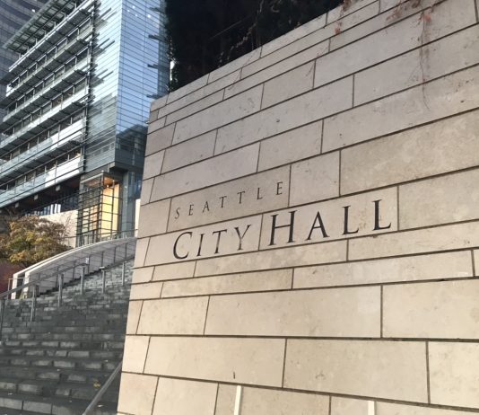 2022 Seattle Solidarity Budget Launches Today Downtown Seattle wall with City Hall sign on it and buildings in the background.