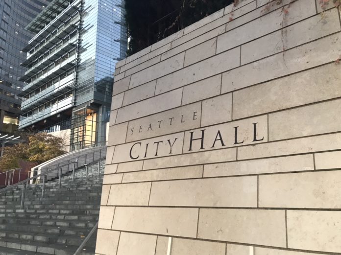 Downtown Seattle wall with City Hall sign on it and buildings in the background.