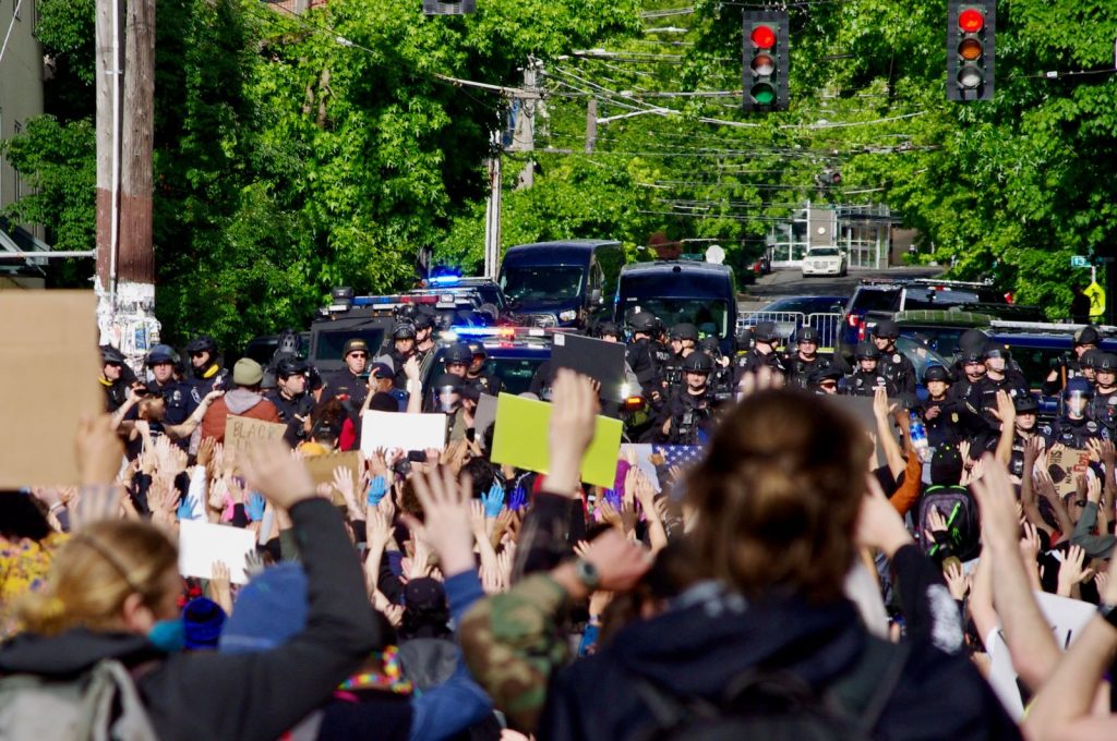 Protestors gather behind a police barricade at the East Precinct building, chanting “Hands up, don’t shoot,” on Sunday, May 31.