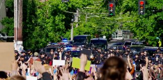 Protestors gather behind a police barricade at the East Precinct building, chanting “Hands up, don’t shoot,” on Sunday, May 31.