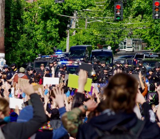 Durkan Declares Seattle Fed-Free, but Her Own Violent ‘Troops’ Dig In Protestors gather behind a police barricade at the East Precinct building, chanting “Hands up, don’t shoot,” on Sunday, May 31.
