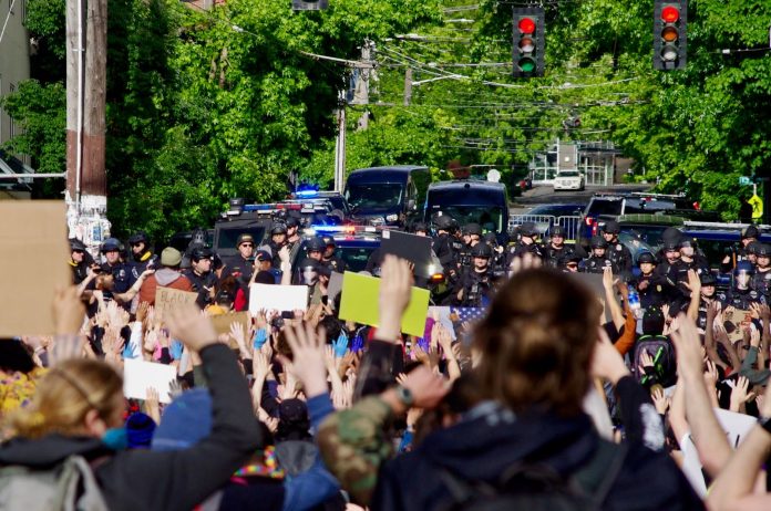 East Precinct on Sunday - Ethan Campbell Protestors gather behind a police barricade at the East Precinct building, chanting “Hands up, don’t shoot,” on Sunday, May 31.