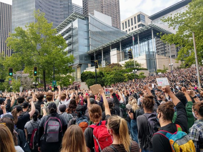 Protesters react with fists raised in solidarity as Nikkita Oliver takes the stage at City Hall on Wednesday June 3rd. (Photo by Doug Trumm)