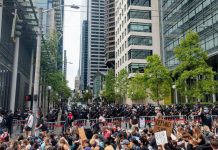 Seattle City Council Passes 2021 Budget with 18% Cut to Police Department The view of Fifth Avenue with a cordon of police officers brandishing billy clubs protecting the block in front of city hall and a stream of protests headed down James Street.