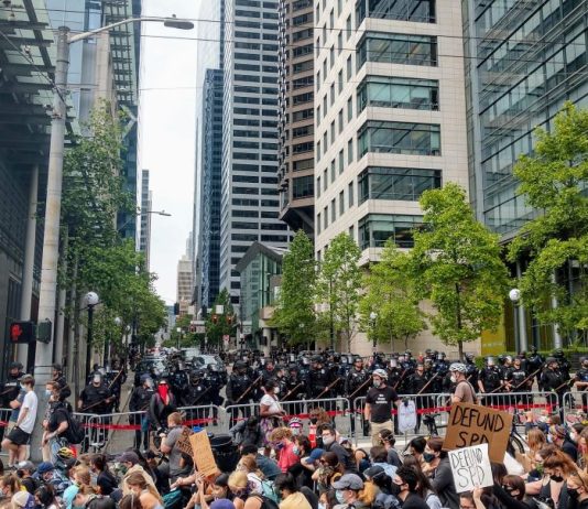 MLK County Labor Council Expels Seattle Police Guild as Contract Showdown Looms The view of Fifth Avenue with a cordon of police officers brandishing billy clubs protecting the block in front of city hall and a stream of protests headed down James Street.