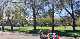 Two young kids on trikes in an open street.