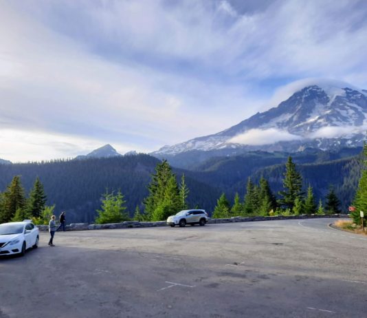 Mount Rainier National Park Seeks Input to Guide Access Upgrades Clouds crown Mount Rainier as a few cars stop for passengers to take in the view.