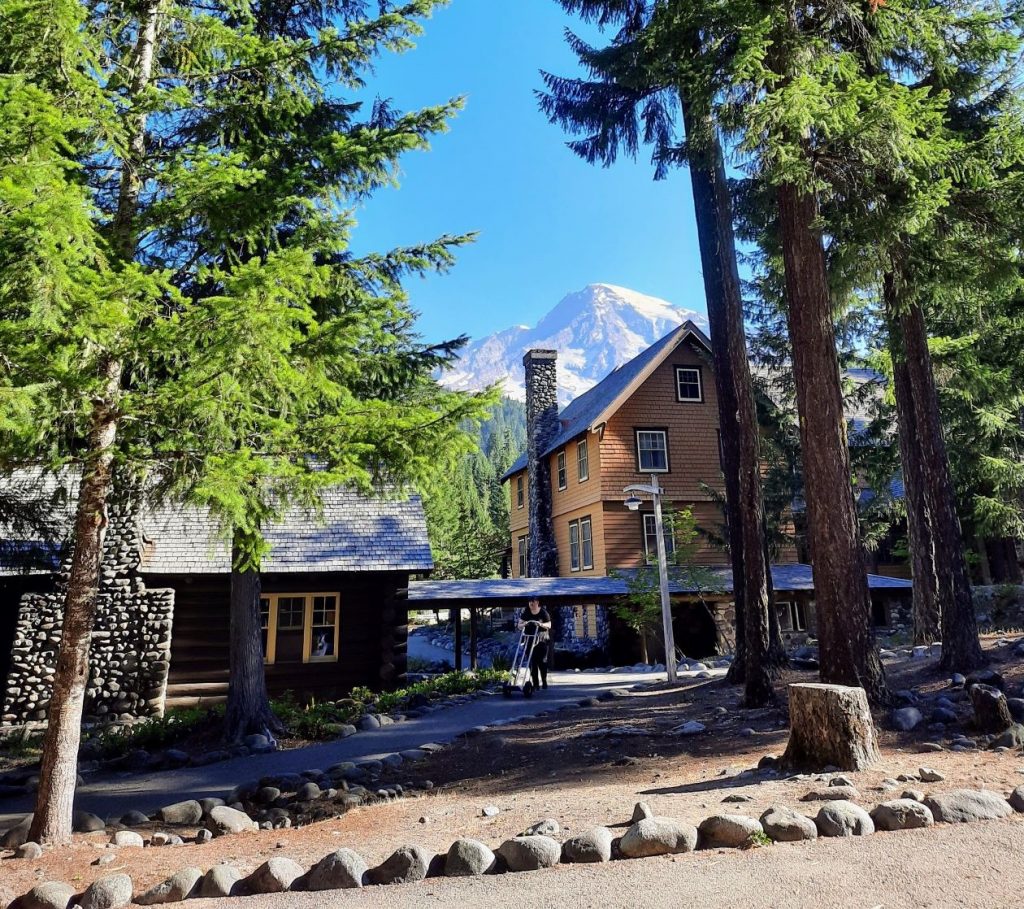 Some Douglas firs and Mount Tahoma frame National Park Inn wooden lodge in Longmire.