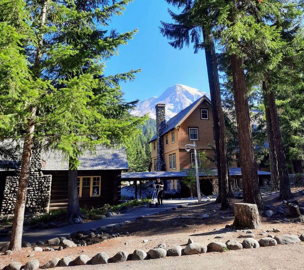 Some Douglas firs and Mount Tahoma frame National Park Inn wooden lodge in Longmire.