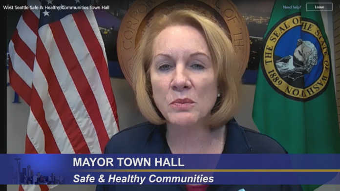 Mayor Durkan flanked by the American flag and Washington state flag.