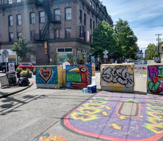 Join Seattle Greenways at Our Meetup Tuesday to Discuss Open Streets and Moving Beyond Enforcement The B from the Black Lives Matter street mural next to barricades with Oddfellows building in the background.
