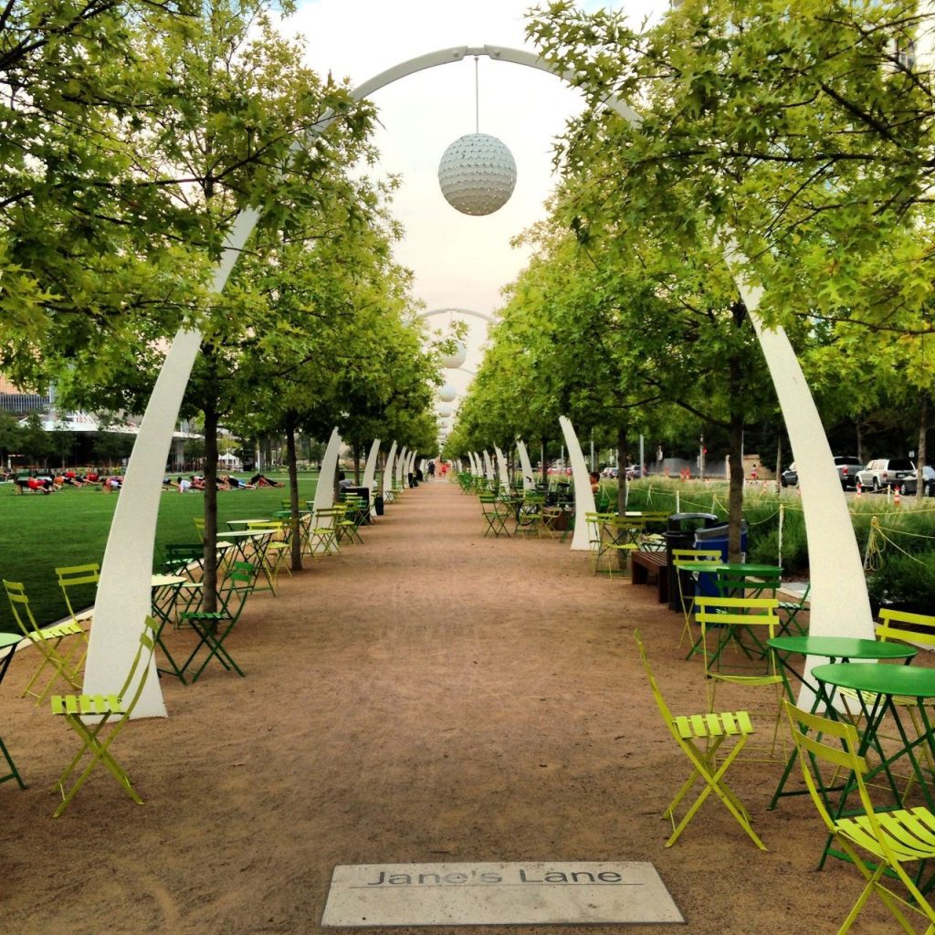 A gravel path flanked by a row or arches with a globe on the nearest one.