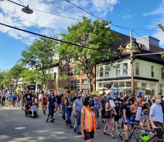 Dear Seattle City Council: Override Mayor Durkan’s Veto and Divest from Racist Policing Protesters marching on Ballard Avenue with signs