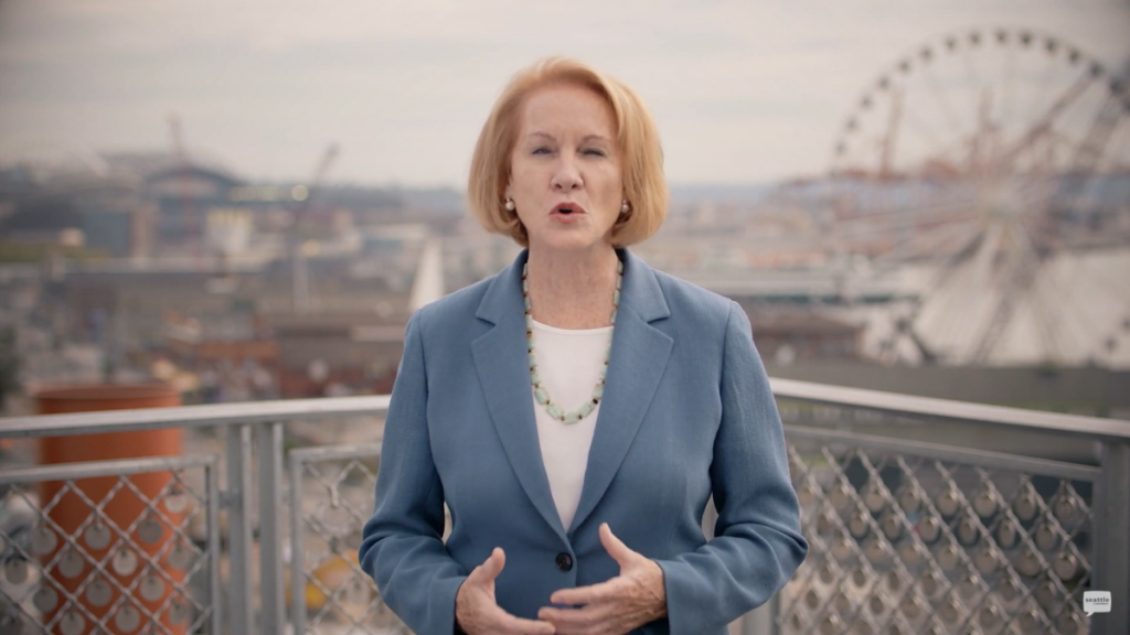 Mayor Durkan with ferris wheel and Seattle waterfront in background.