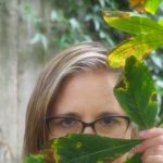 Jennifer Calkins posing behind a leafy plant