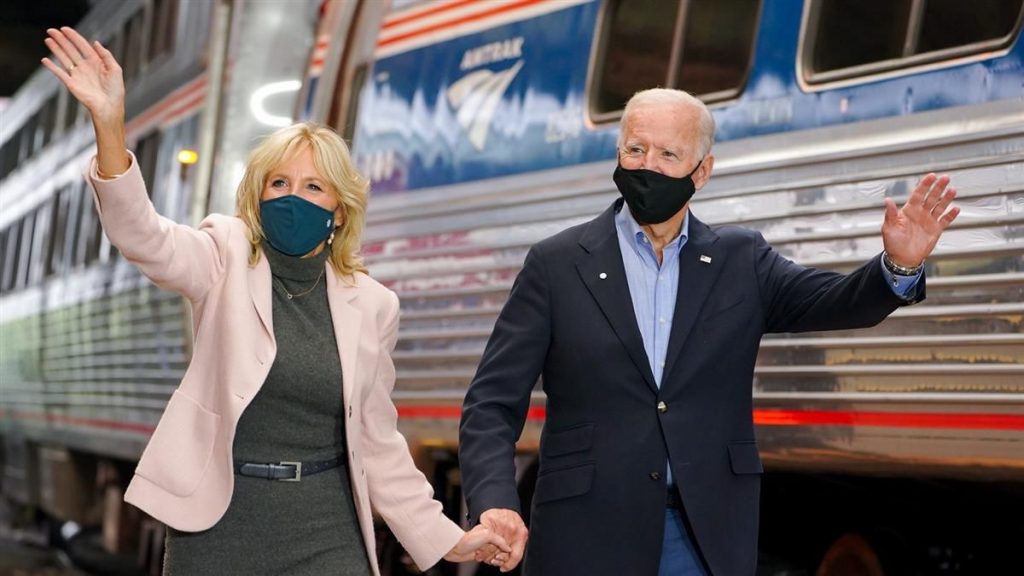 A photo Jill and Joe Biden walking beside a passenger train. 