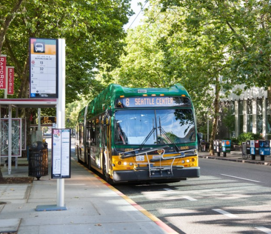 2021 Fall Transit Service Changes Are Coming to Puget Sound Agencies A photo of a King County Metro bus pulling into a bus station on a tree-lined street.